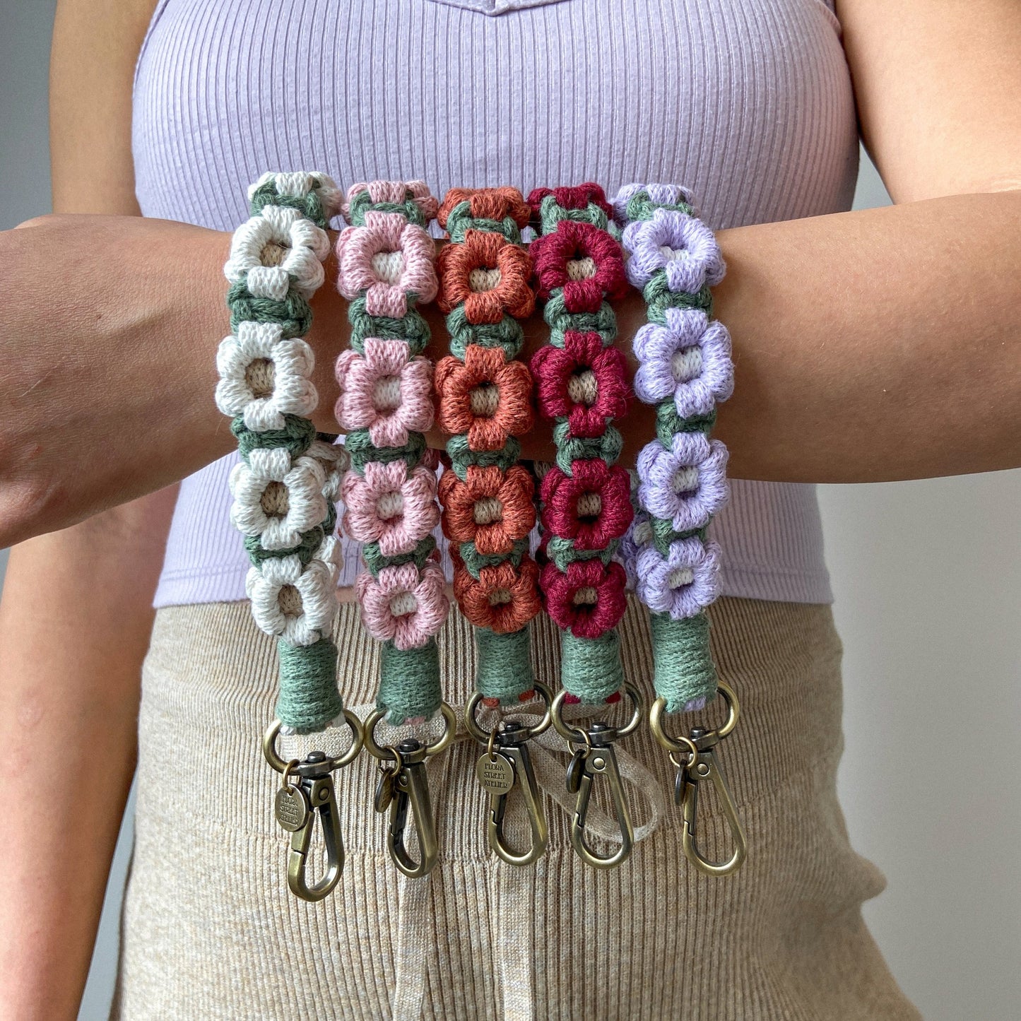 macrame daisy keychains on an arm