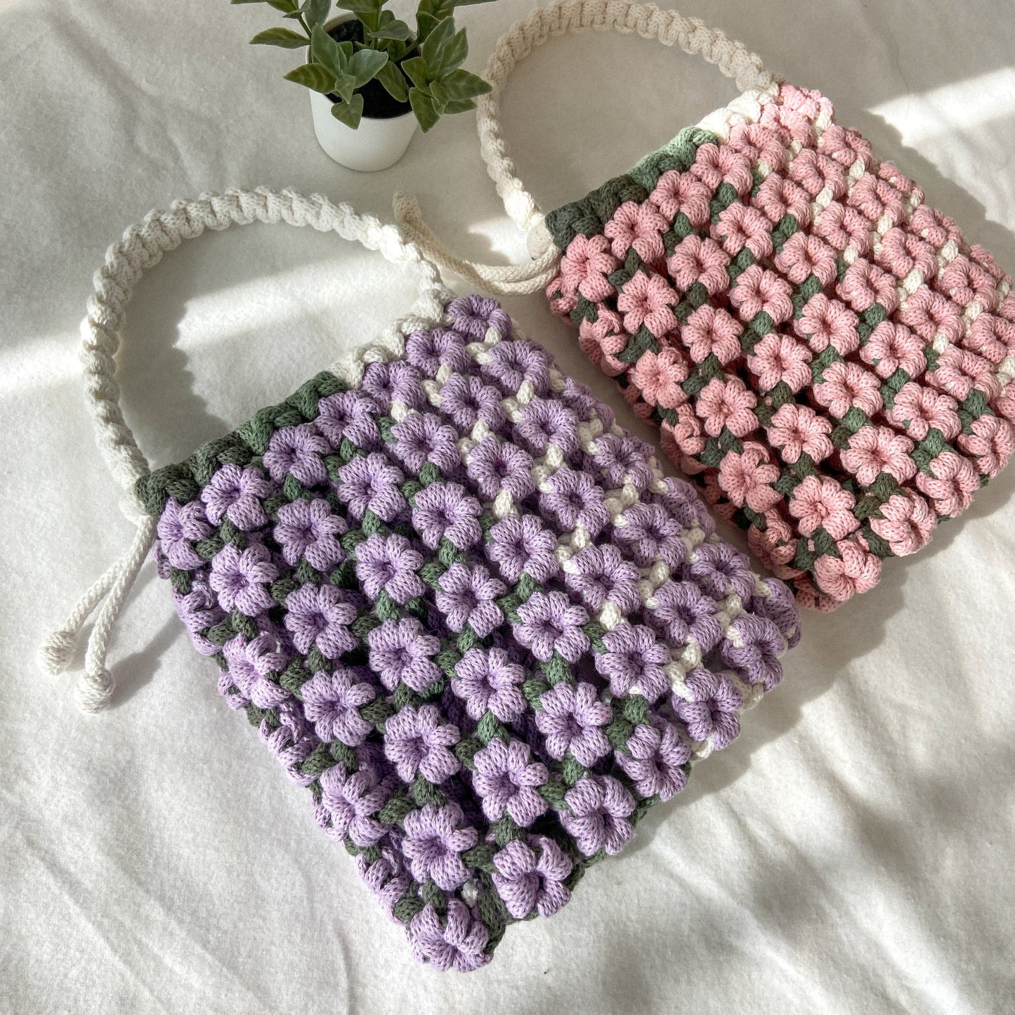 Handwoven macrame flower top handle bag made from sustainable cotton rope, boho summer accessory.
One in pink, one in purple