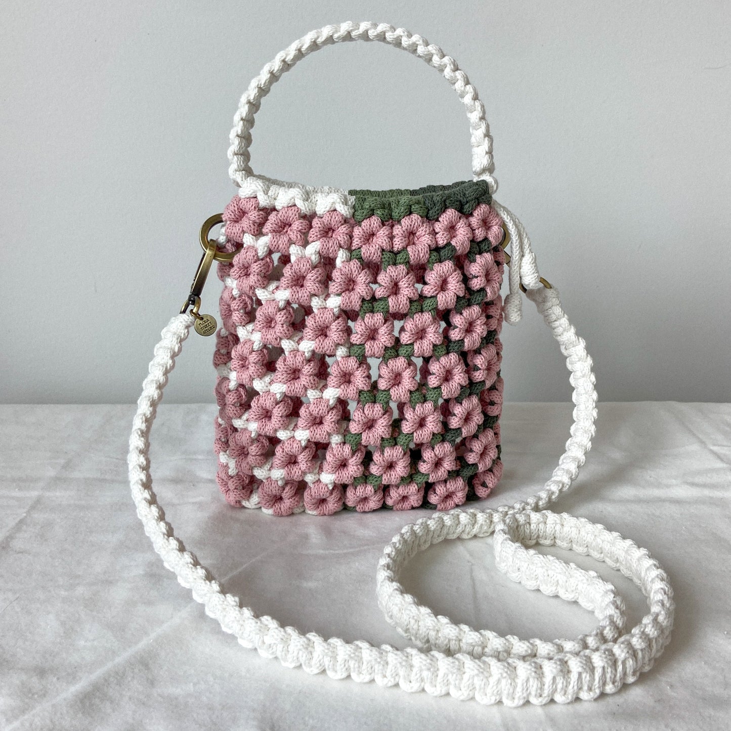 Crocheted handbag with pink and green pattern on a light gray surface