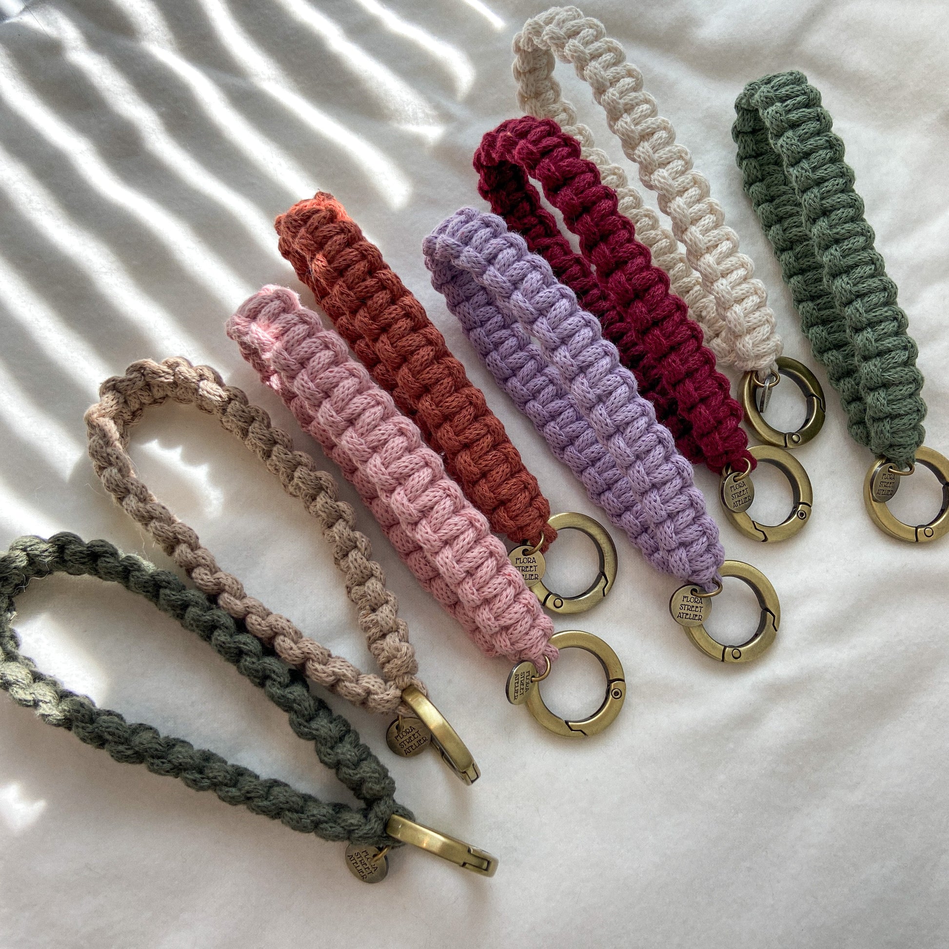 Hand knotted macrame wristlet strap with metal clasp, handmade by Flora Street Atelier, crafted in Canada with recycled cotton in white, pink, sunset, burgundy, sage, dark green, beige color
