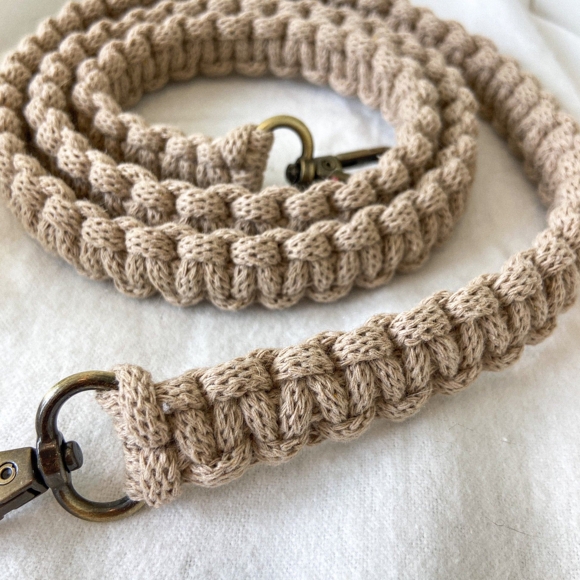 Macrame beige bag strap with brass clasps on a light background
