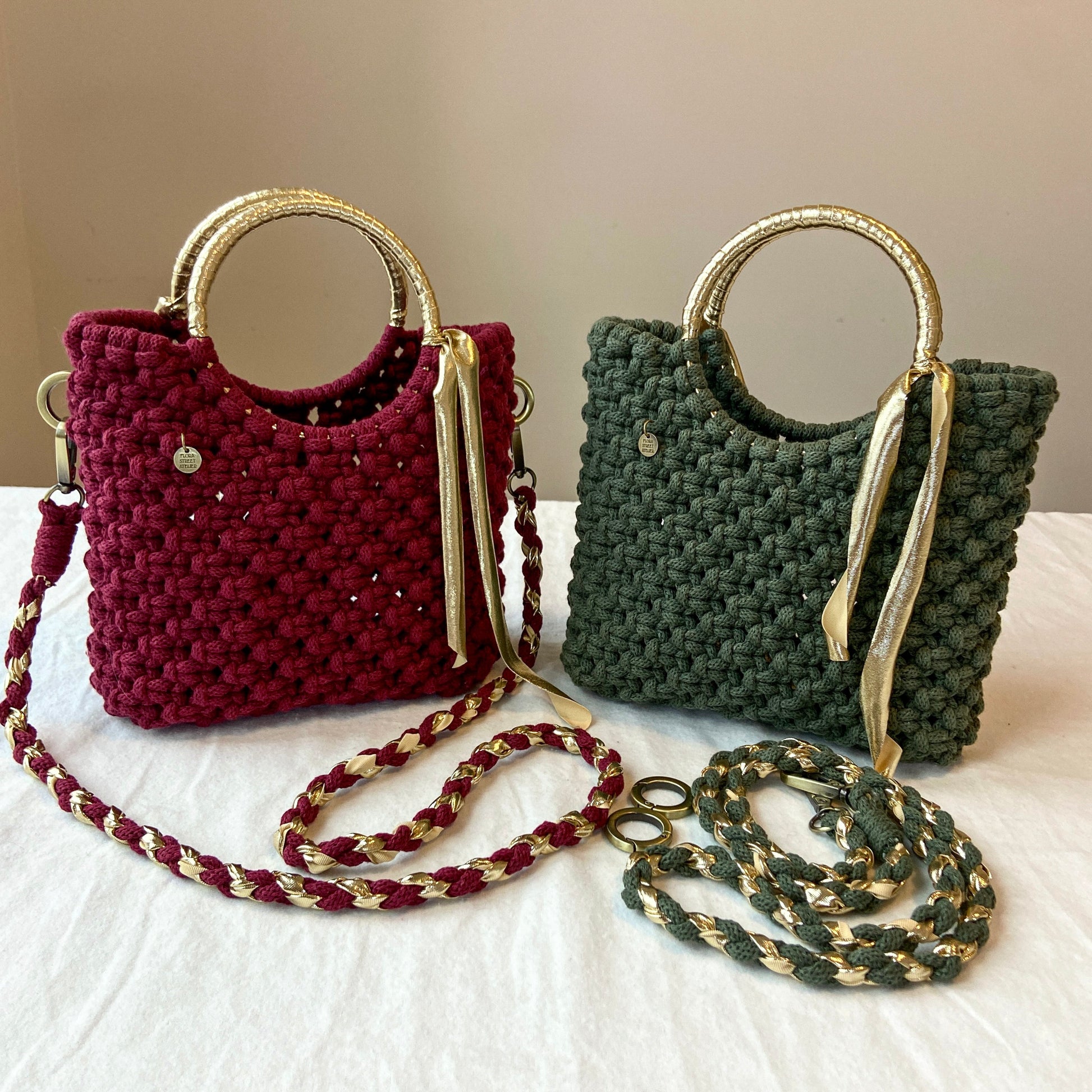 Two macrame handbags, one red and one green, with gold handles and chains on a white surface.