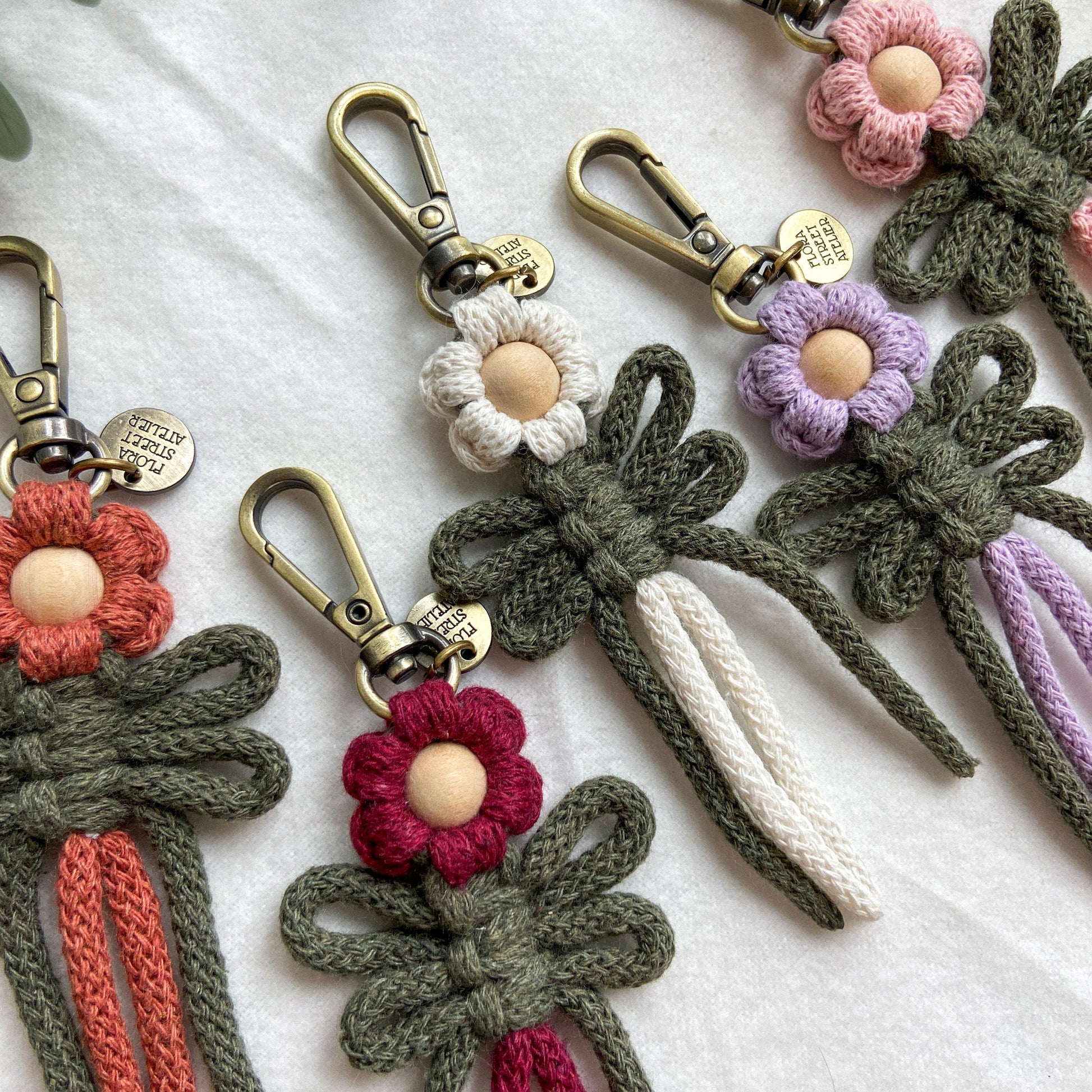 A collection of macrame key rings with floral patterns, featuring different colors and brass hardware.